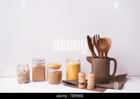 Set di utensili da cucina con semole sul tavolo vicino a muro bianco Foto Stock