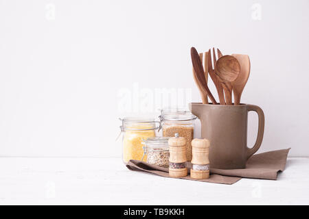 Set di utensili da cucina con semole sul tavolo vicino a muro bianco Foto Stock