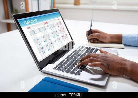Close-up di imprenditrice la scrittura di pianificazione nel diario del calendario sulla scrivania Foto Stock
