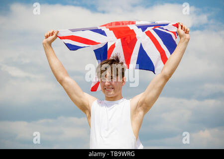 Giovane adulto maschio caucasico tenendo premuto su una spiaggia tiene la bandiera della Gran Bretagna Foto Stock