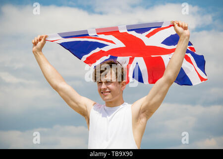 Giovane adulto maschio caucasico tenendo premuto su una spiaggia tiene la bandiera della Gran Bretagna Foto Stock
