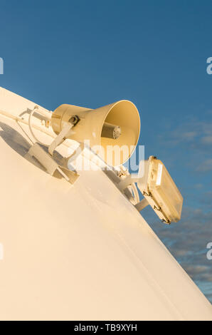 Altoparlante esterno e apparecchio di illuminazione montata su metallo bianco parete della nave da crociera. Foto Stock