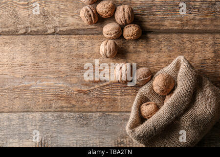 Sacco con gustosi noci sul tavolo di legno Foto Stock