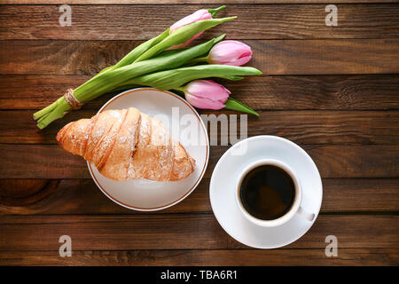 Bouquet di tulipani bellissimo, croissant e caffè su sfondo di legno Foto Stock