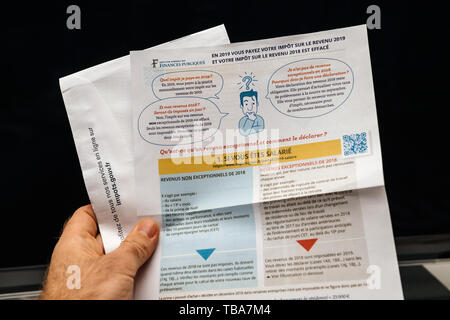 Parigi, Francia - il Apr 9, 2019: uomo lettura tenendo la dichiarazione des revenus reddito istruzioni di dichiarazione prima della presentazione pre-compilata Reddito dichiarazione alle autorità francesi e le imposte sul reddito istruzioni per l'anno precedente Foto Stock