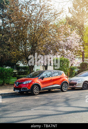 Parigi, Francia - Aprile 3, 2017: Rosso Renault Captur SUV parcheggiato su una strada soleggiata sotto in bloom tree Foto Stock