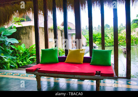 BALI, INDONESIA - febbraio circa, 2019. Un legno di teak di stile Balinese panca batavia accanto a un lago. Un lusso confortevole concetto di viaggio per rilassarsi Foto Stock