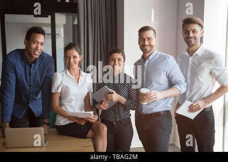 Sorridente team multietnica stand facendo foto di gruppo insieme Foto Stock