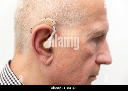 Hearing Aid nell'orecchio di età compresa tra uomo vecchio. Senior utilizzando i moderni apparecchi acustici Foto Stock