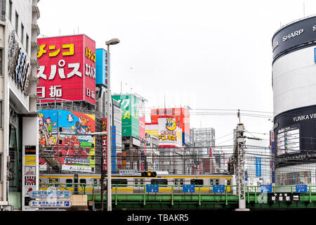 Tokyo, Giappone - 30 Marzo 2019: Downtown con colorati rosso verde segni in Shinjuku con edifici con la metropolitana e il treno è in movimento in centro città cityscape Foto Stock