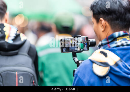 Tokyo, Giappone - 30 Marzo 2019: mercato esterno street di Tsukiji vicino a Ginza con uomo azienda telefono stabilizzatore di sospensione cardanica riprese video di persone Foto Stock