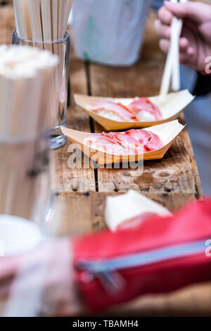 Tokyo, Giappone esterno strada del mercato di Tsukiji Ginza con persone closeup mangiare sushi sashimi con bacchette sul tavolo esterno Foto Stock