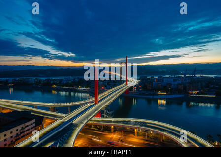 Sulle rive del fiume Xijia nel sole di setting, le luci del ponte sul Fiume Yangtze sono accesi e il cielo azzurro riflette l'altra. Foto Stock