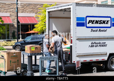 Montgomery, Stati Uniti d'America - 21 Aprile 2018: Città in Alabama street vicino alla città di marciapiede e persone in movimento movers uomini scatole da imballaggio in Penske Truck Foto Stock