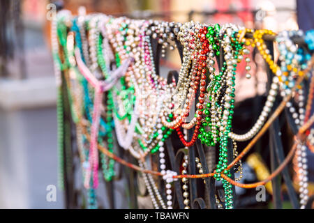 New Orleans, STATI UNITI D'AMERICA closeup del Mardi Gras beads appeso alla recinzione da colorati la costruzione di casa e nessuno sul marciapiede Foto Stock