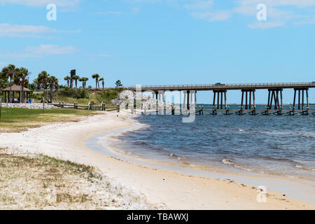 Navarra, Stati Uniti d'America - 24 Aprile 2018: Navarra park coast beach, persone che camminano su wharf pier boardwalk dall'acqua dell'oceano con Pensacola bay bridge, Golfo di Mexi Foto Stock