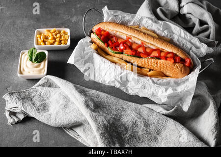 Composizione con gustosi hot dog su sfondo grigio Foto Stock