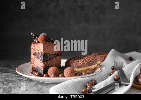 Piastra con il pezzo di gustosa torta al cioccolato e caramelle sul tavolo Foto Stock