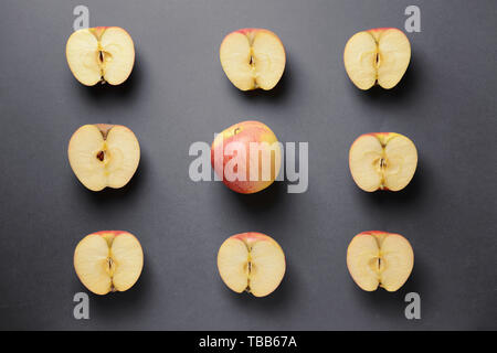 Un intero apple tra quelli tagliati su sfondo grigio. Concetto di unicità Foto Stock