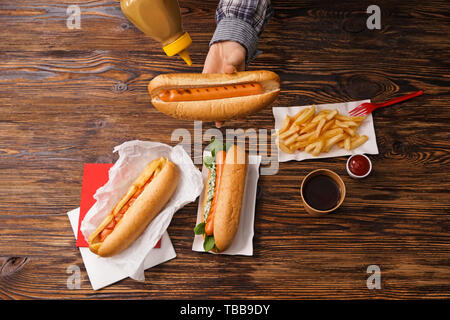 Donna di mostarda di spremitura dalla bombola sul gustoso hot dog Foto Stock