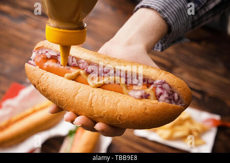 Donna di mostarda di spremitura dalla bombola sul gustoso hot dog, primo piano Foto Stock
