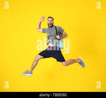 Giovane uomo sportivo jumping contro il colore di sfondo Foto Stock