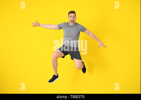 Giovane uomo sportivo jumping contro il colore di sfondo Foto Stock