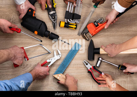Vista dall'alto di persone di mano azienda attrezzi di falegnameria sulla scrivania in legno Foto Stock