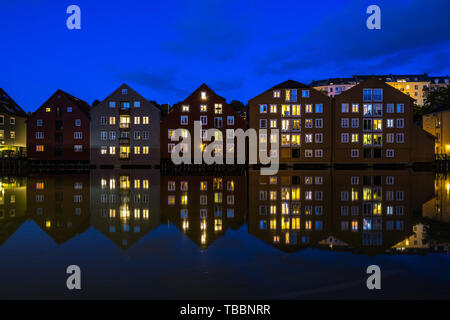 Ora blu vista di vecchi granai convertiti in edifici residenziali lungo il fiume Nidelva, Trondheim, Norvegia Foto Stock