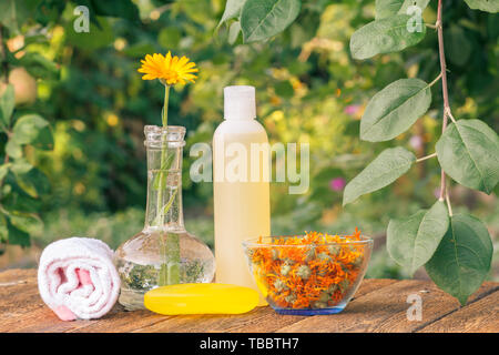 Prodotti per il benessere e gli accessori. Asciugamani, sapone e la bottiglia di plastica con estratto di calendula, calendula fiori in un pallone di vetro ed il vaso con fiori secchi di ca Foto Stock