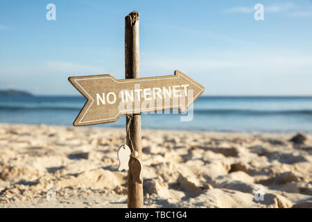 Close-up di No Internet legno freccia direzionale polo di segno sulla spiaggia sabbiosa Foto Stock