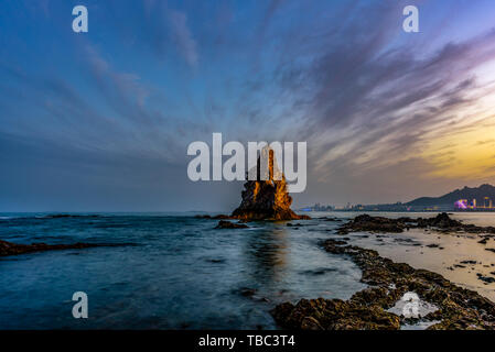 Pietra di Qingdao vecchio è un famoso paesaggio balneare a Qingdao. La marea si ritira la sera e il vecchio uomo pietra è più affascinante contro lo sfondo del tramonto. Foto Stock
