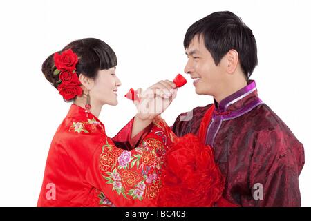In questa foto creative, una coppia di sposi in luna di miele cinese, sia vestito in cinese tradizionale costumi di nozze, bevande cross-liquore a tazza durante la loro cerimonia di nozze in Cina a Shanghai. Foto Stock