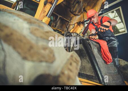 Caucasica attrezzature pesanti meccanico nel suo 30s luce di riparazione peso Bulldozer. Foto Stock