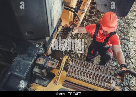 Macchinari pesanti operatore salendo sul carrello metallico scaletta. Il mio carrello di guida. Foto Stock