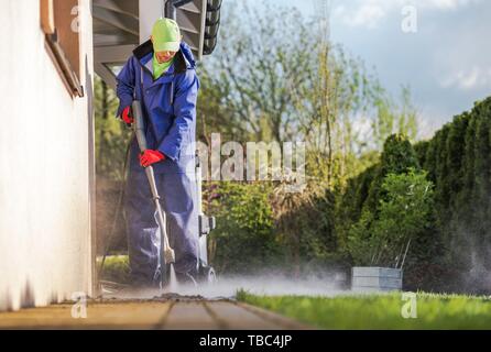 Pulizia casa di mattoni del cortile percorsi utilizzando la rondella a pressione. Uomini caucasici e la molla di manutenzione. Foto Stock