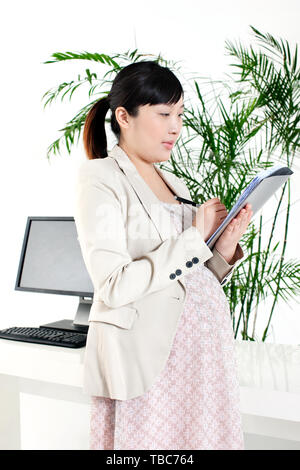 Una donna incinta bianco-collare lavoratore. Foto Stock