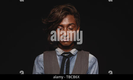 Chiusura del giovane africano con gli occhi chiusi. Moda maschile africana isolato su sfondo nero. Foto Stock