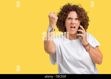 Medio ager senior donna parlando sullo smartphone su sfondo isolato infastiditi e frustrato grida con rabbia, crazy e urla con mano sollevata Foto Stock