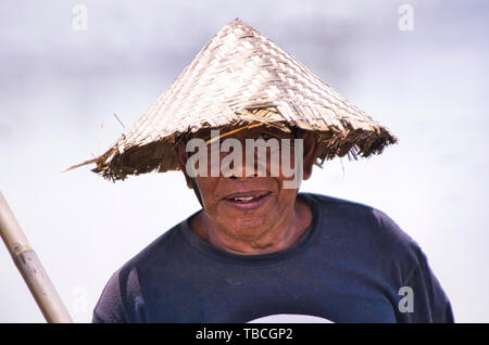 UBUD, Bali, Indonesia - febbraio circa, 2019. Un Indonesia non identificato uomo che vivono al di fuori della città di Ubud chi indossa leaf hat e guardando la camma Foto Stock