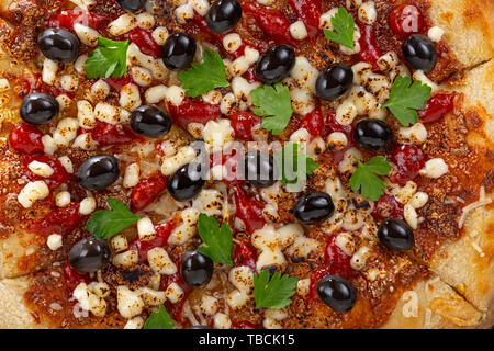 Pizza di close-up vista dall'alto. Tradizionale pizza italiana con olive, mozzarella, verdi e salsa di pomodoro Foto Stock