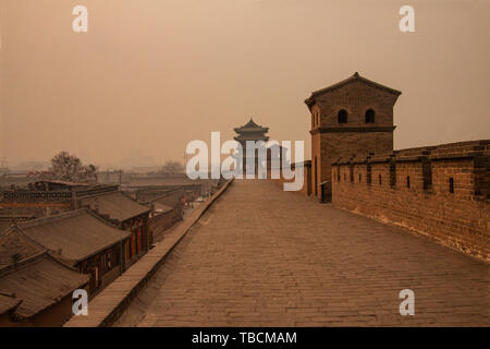 Vecchio muro con ciascuna delle torri che circondano la città antica di Pingyao. Immagine girato su un nebbioso giorno con smog proveniente dal riscaldamento con carbone e torba. Foto Stock