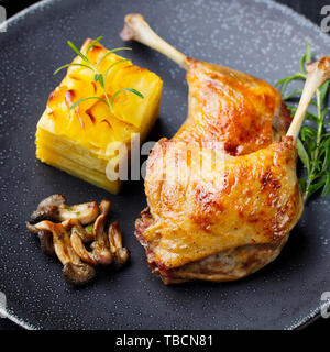 Gambe di Anatra confit con patate gratinate e fungo. Close up. Foto Stock