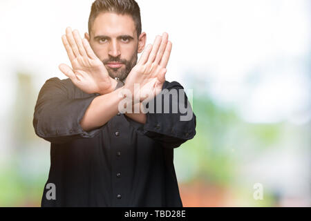 Giovane sacerdote cristiano su sfondo isolato rifiuto espressione bracci di attraversamento e di palme facendo segno negativo, volto arrabbiato Foto Stock