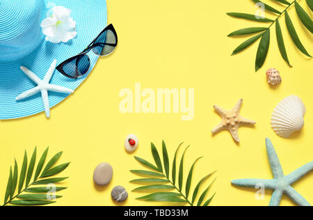 Sfondo tropicale. Palme rami, hat con stella marina e conchiglia su sfondo giallo. Il viaggio. Spazio di copia Foto Stock