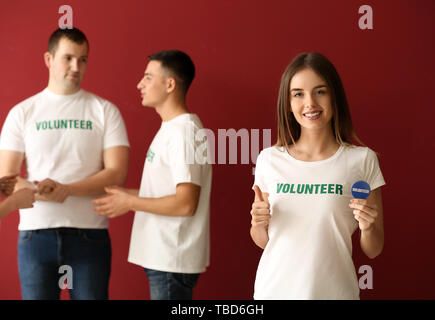 Giovani volontari di sesso femminile e il suo team sul colore di sfondo Foto Stock