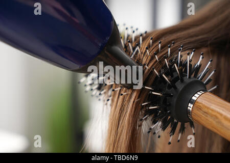 La spazzolatura di lunghi capelli femmina in salone, primo piano Foto Stock