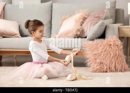 Carino little ballerina mettendo a punto le scarpe a casa Foto Stock