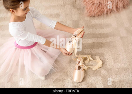 Carino little ballerina mettendo a punto le scarpe a casa Foto Stock