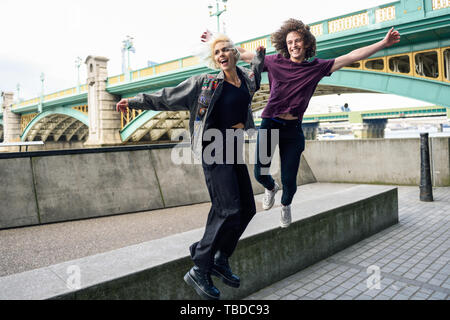 Funny giovane junping vicino il Southwark ponte sul fiume Tamigi, Londra Foto Stock